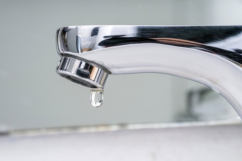  What Problems Can a Leaky Faucet Cause? Close up photo of a faucet leaking water.