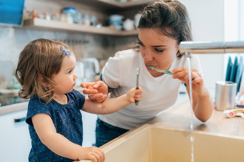 Why Get a Water Filtration System? Photo of a mother and toddler daughter brushing their teeth together.